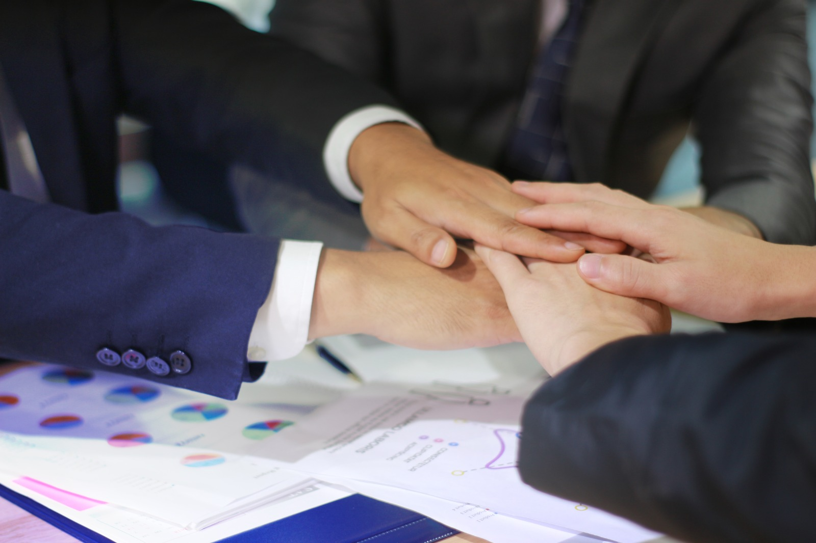 Consulting team joining hands over business documents
